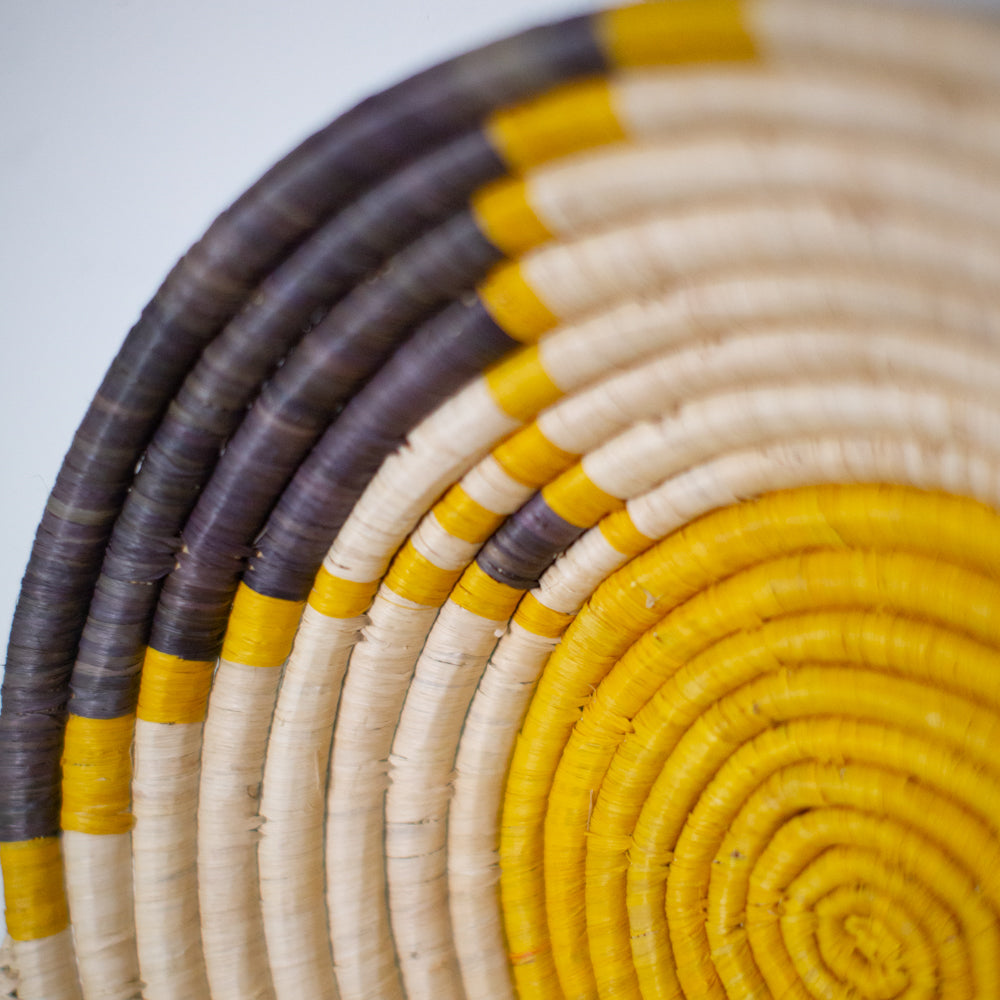 JustOne's yellow wall basket with grey and tan design, handwoven in Uganda