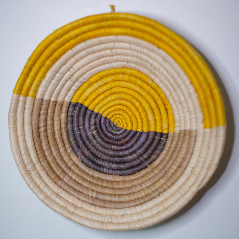 JustOne's yellow, tan, and grey wall basket, handwoven in Uganda