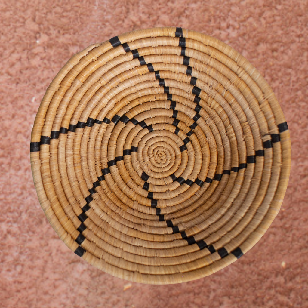 JustOne's tan basket with black lines handwoven in Uganda