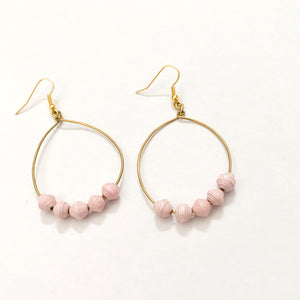 JustOne's brass hoop earrings with five pink paper beads on the bottom of the hoop, handcrafted in Uganda