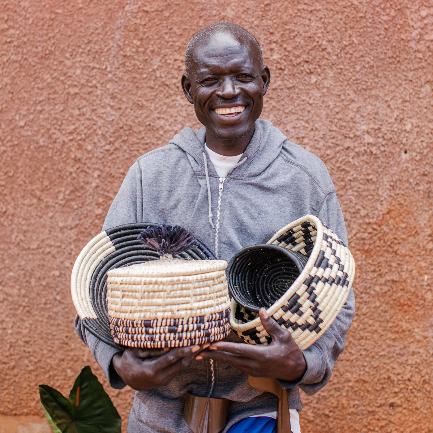 JustOne's natural basket with black details on bottom and lid with a black pompom handle, handcrafted in Uganda