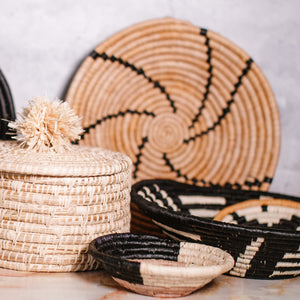 JustOne's small tan basket with black star and yellow border, handwoven in Uganda.