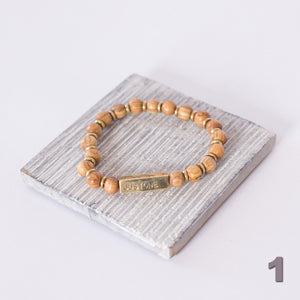 JustOne's stretch bracelet made with handcrafted wooden beads and brass bar that says JustOne, handcrafted in Kenya