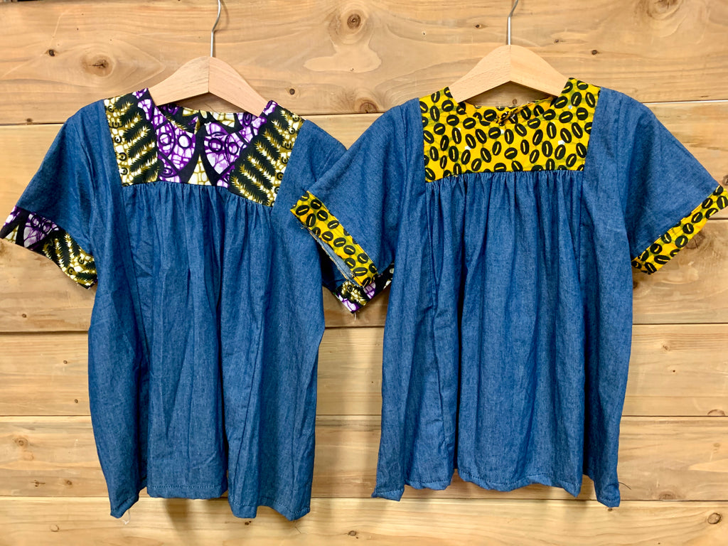 JustOne's small blue dress with design around the collar and cuffs of the sleeves, hand-sewn in Uganda