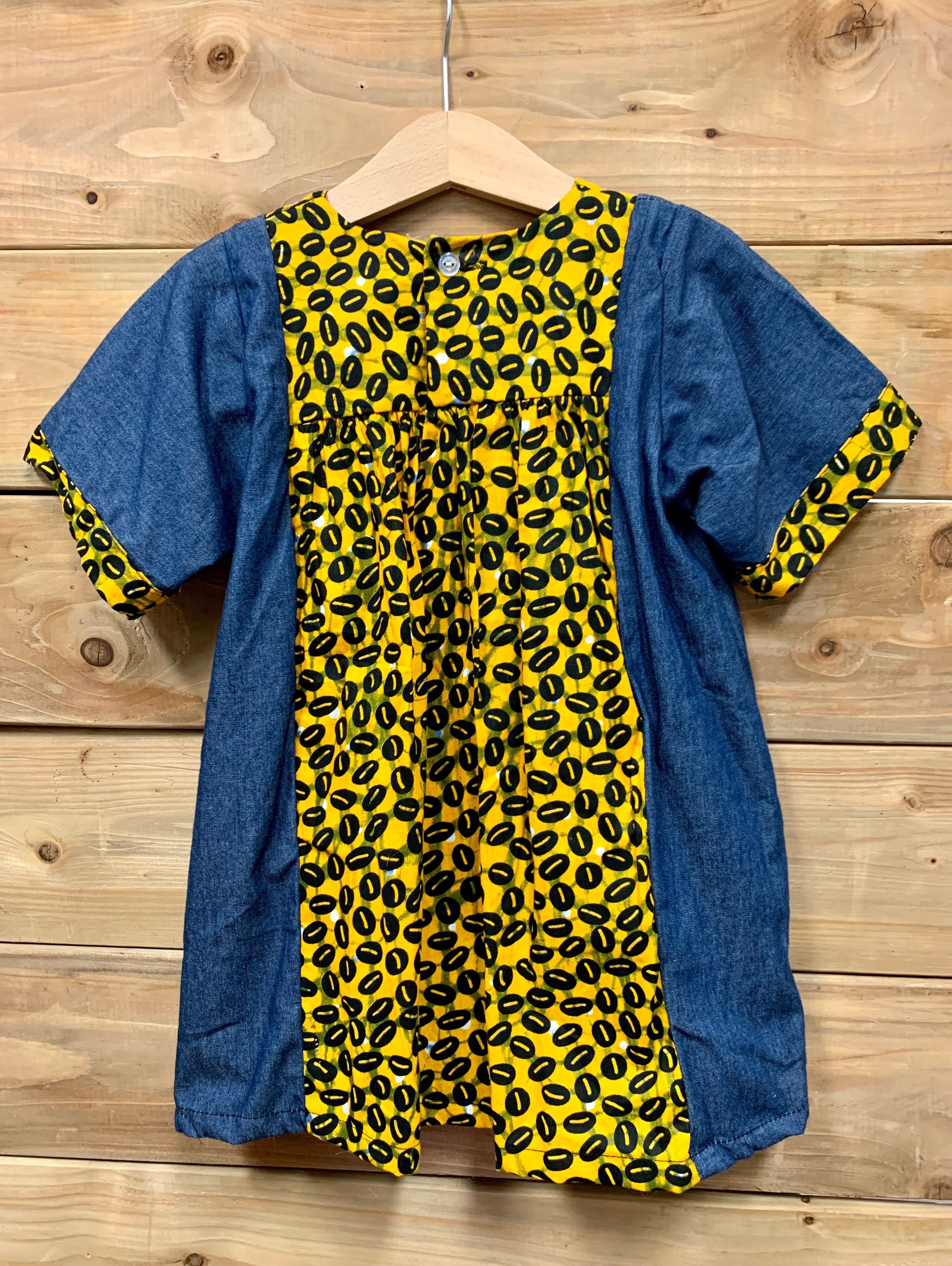 JustOne's small blue dress with design around the collar and cuffs of the sleeves, hand-sewn in Uganda