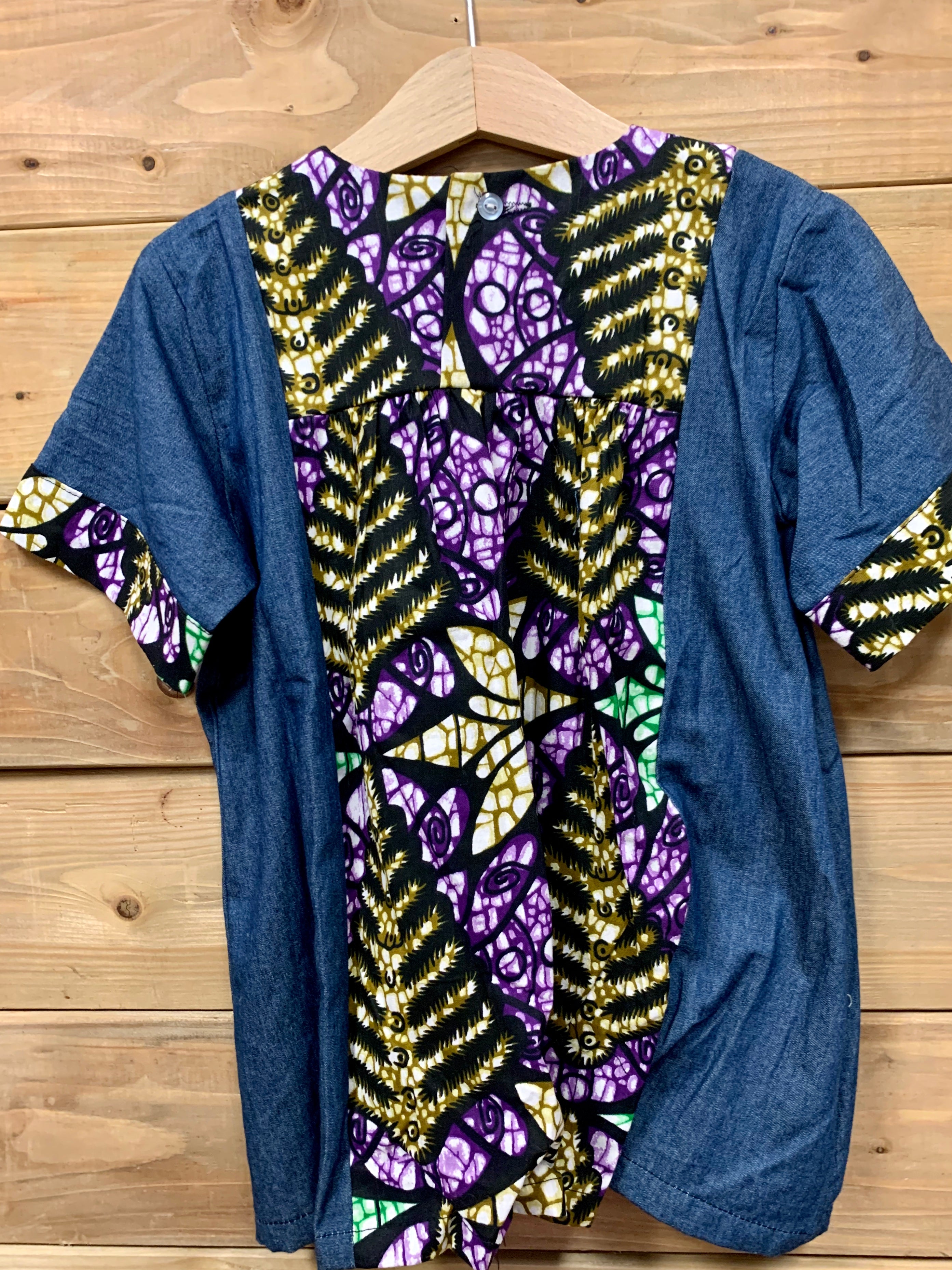JustOne's small blue dress with design around the collar and cuffs of the sleeves, hand-sewn in Uganda