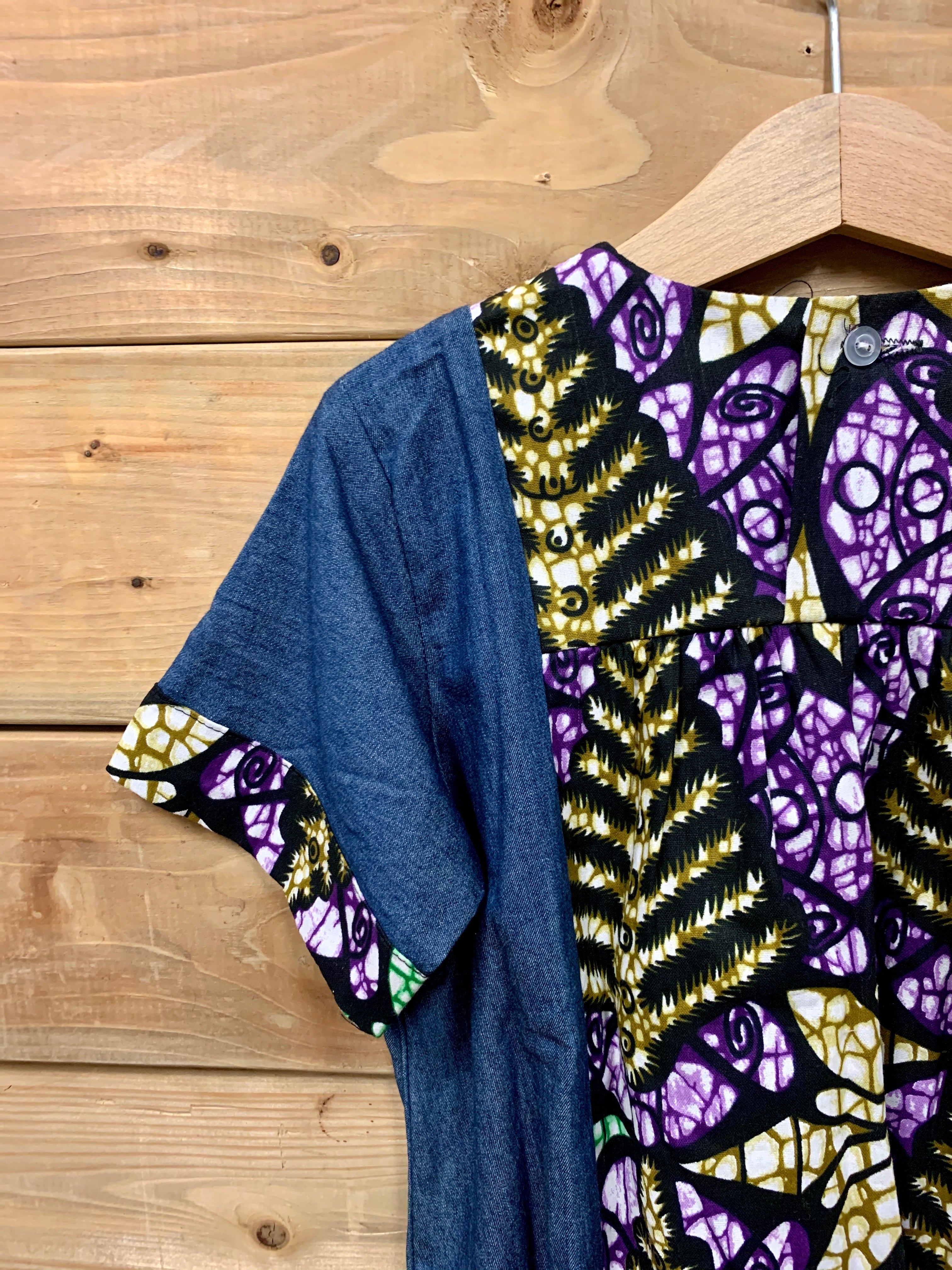 JustOne's small blue dress with design around the collar and cuffs of the sleeves, hand-sewn in Uganda