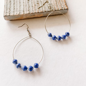 JustOne's silver hoop earrings with five blue paper beads on the bottom of the hoop, handcrafted in Uganda