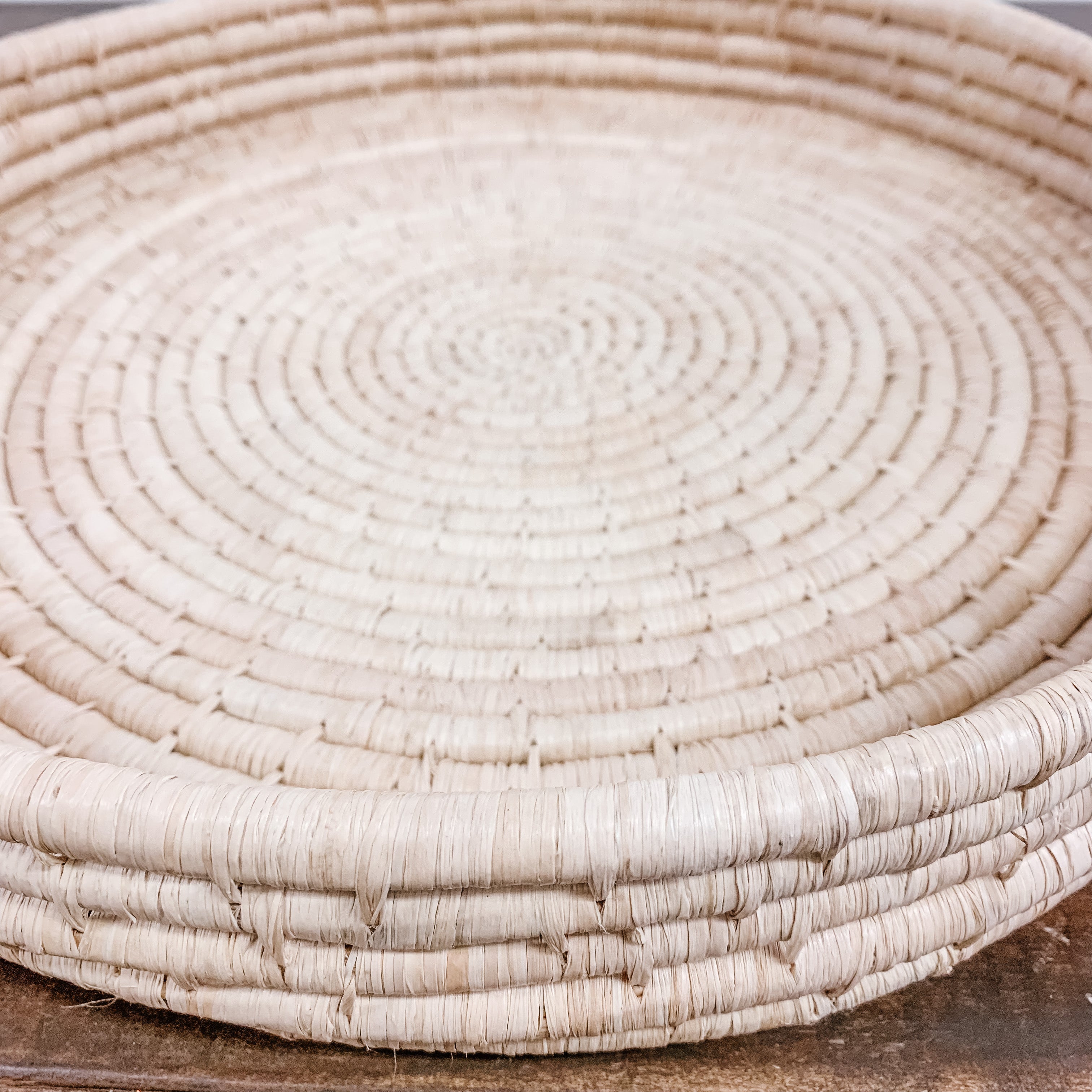 JusrtOne's large, shallow, round basket in tan, handwoven in Uganda