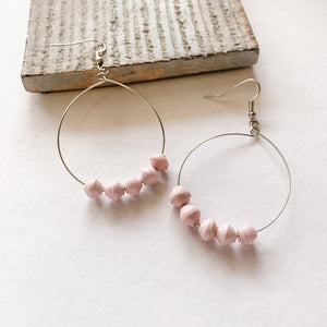 JustOne's silver hoop earrings with five pink paper beads on the bottom of the hoop, handcrafted in Uganda
